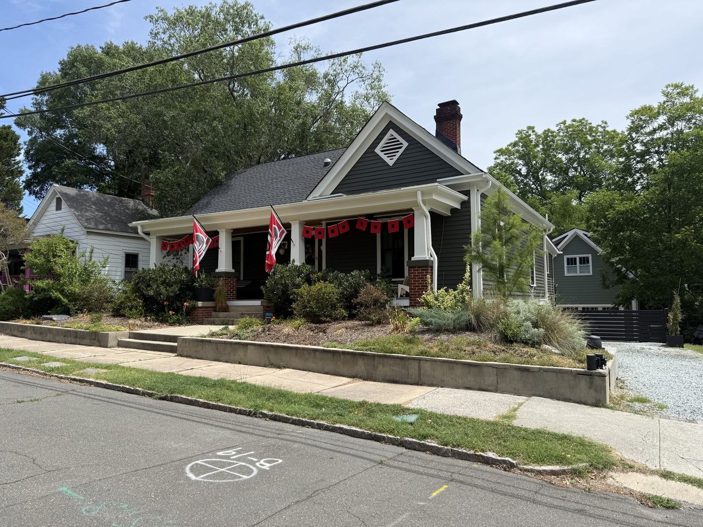 After: the house painted a deep green-gray with white trim, Hurricanes flags on the porch, and a planted front yard.